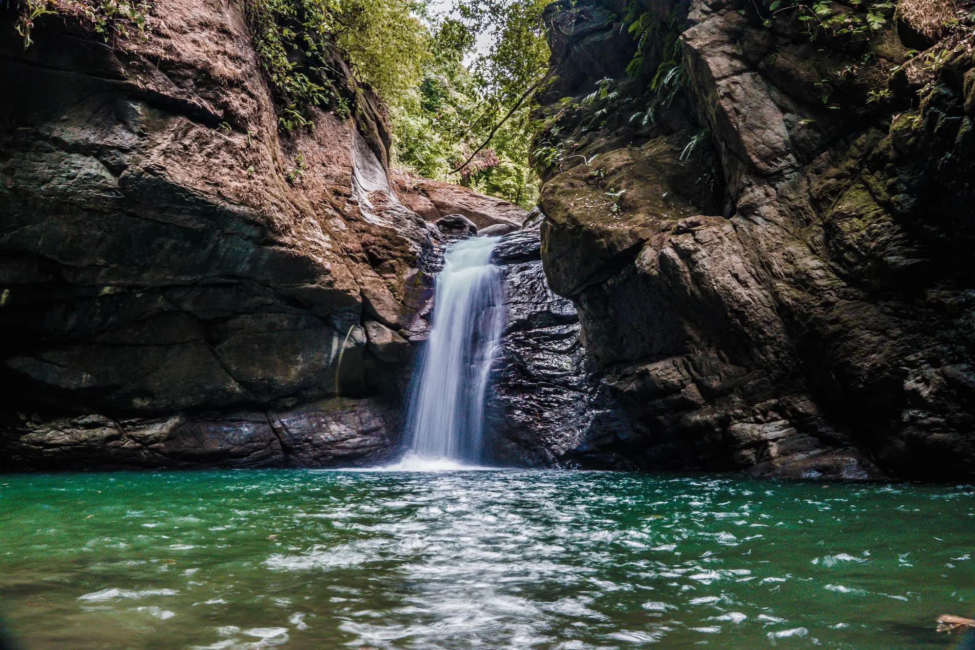 A waterfall pouring into an emerald pool on the Holos land